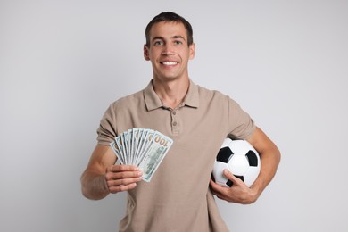 Happy man with money and soccer ball on white background