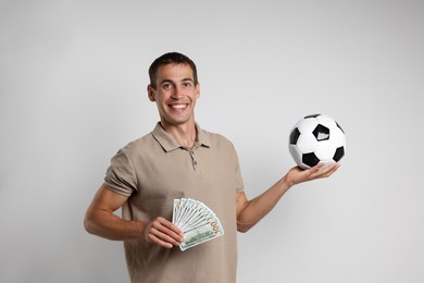 Happy man with money and soccer ball on white background