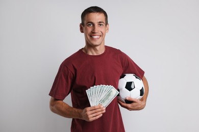 Happy man with money and soccer ball on white background