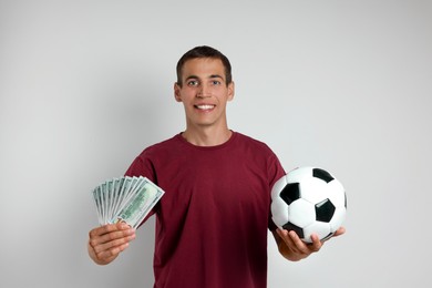 Happy man with money and soccer ball on white background