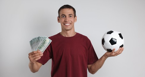 Happy man with money and soccer ball on white background