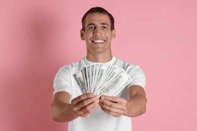 Happy man with money on pink background