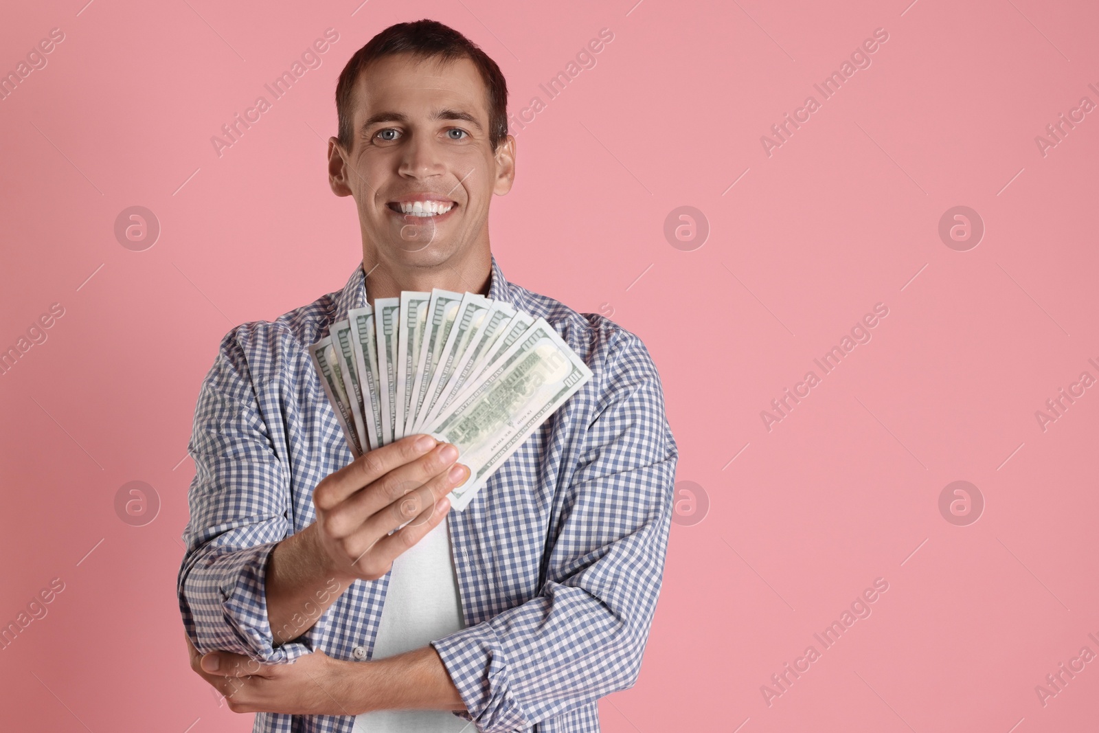 Photo of Happy man with money on pink background, space for text