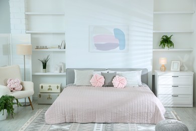 Photo of Large bed, houseplants and decorative elements in room. Stylish bedroom interior