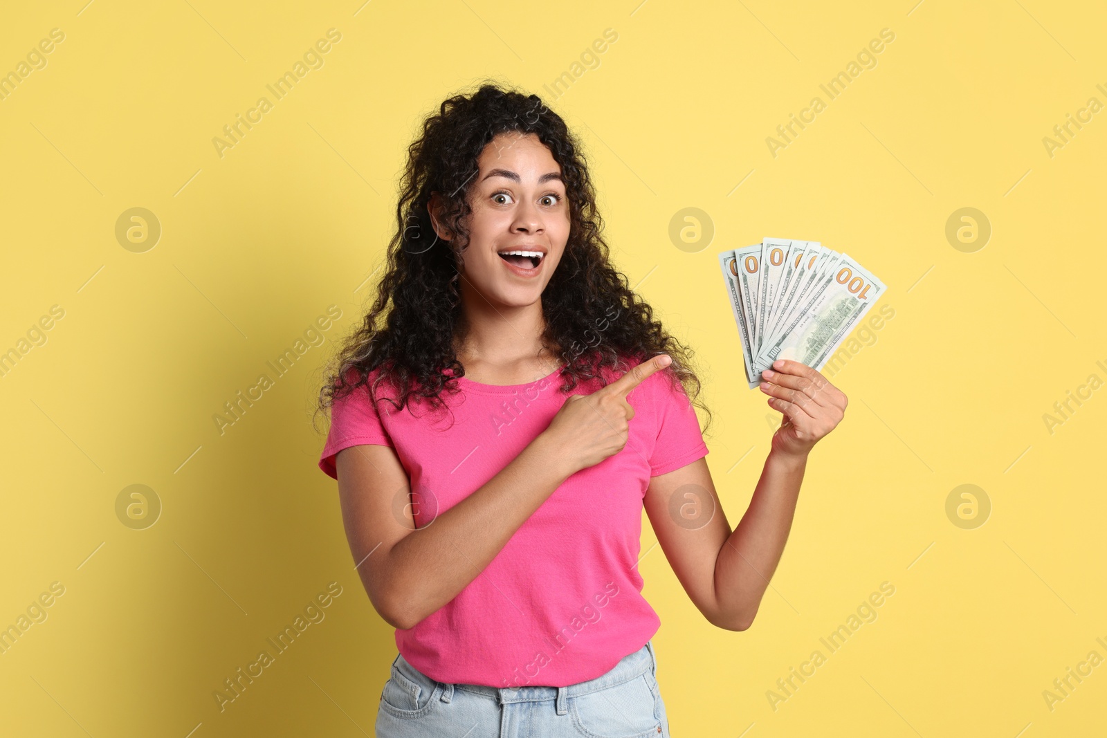 Photo of Happy woman with dollar banknotes on yellow background