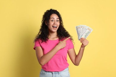 Photo of Happy woman with dollar banknotes on yellow background