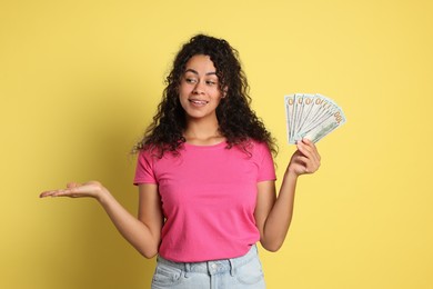 Photo of Happy woman with dollar banknotes on yellow background