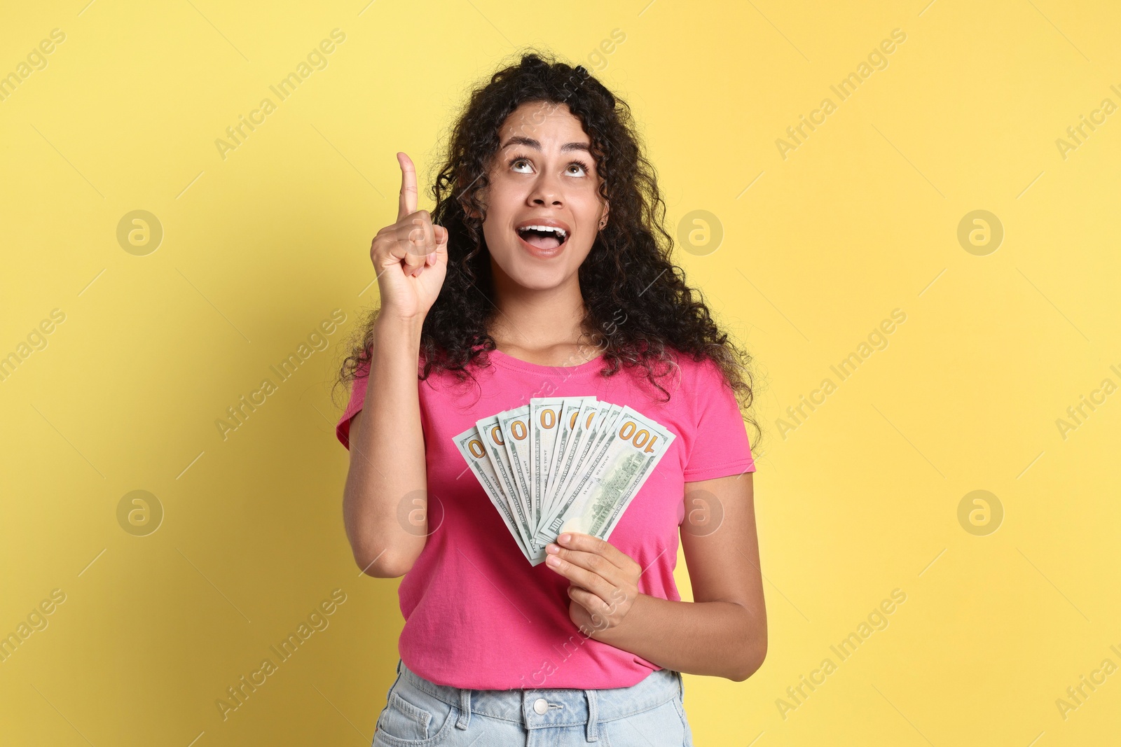 Photo of Happy woman with dollar banknotes on yellow background