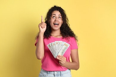 Happy woman with dollar banknotes on yellow background