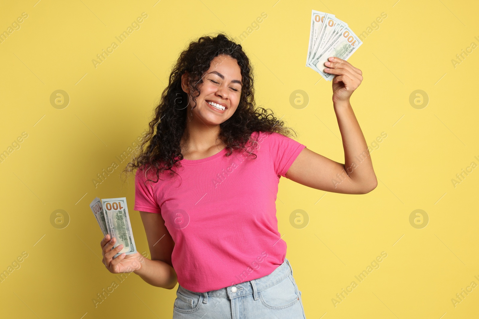 Photo of Happy woman with dollar banknotes on yellow background