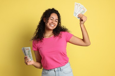 Happy woman with dollar banknotes on yellow background