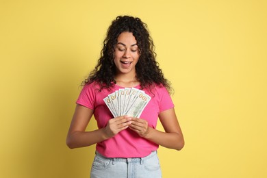 Happy woman with dollar banknotes on yellow background