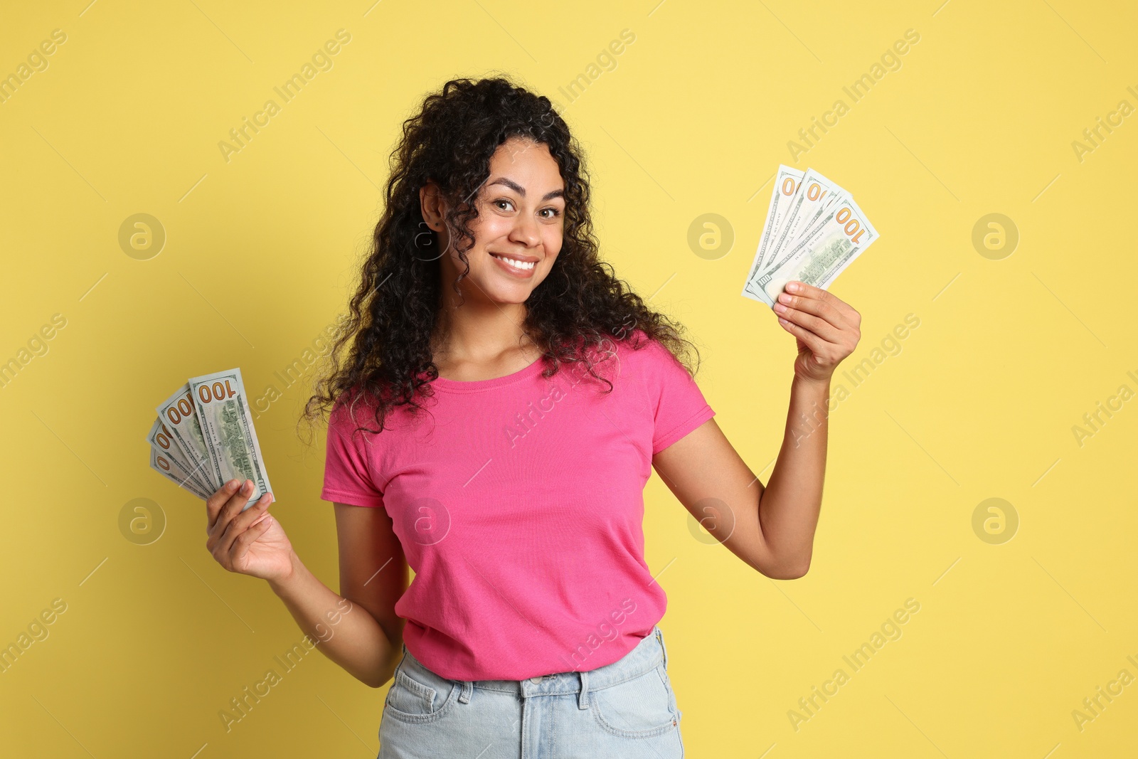 Photo of Happy woman with dollar banknotes on yellow background