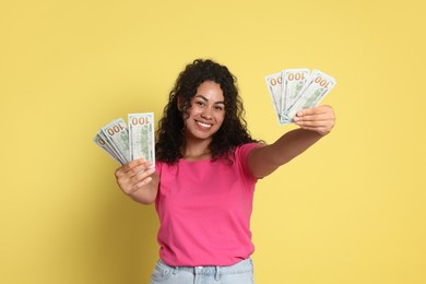 Photo of Happy woman with dollar banknotes on yellow background