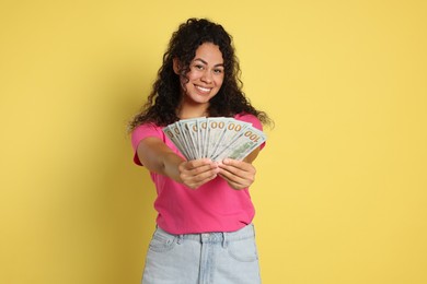 Photo of Happy woman with dollar banknotes on yellow background