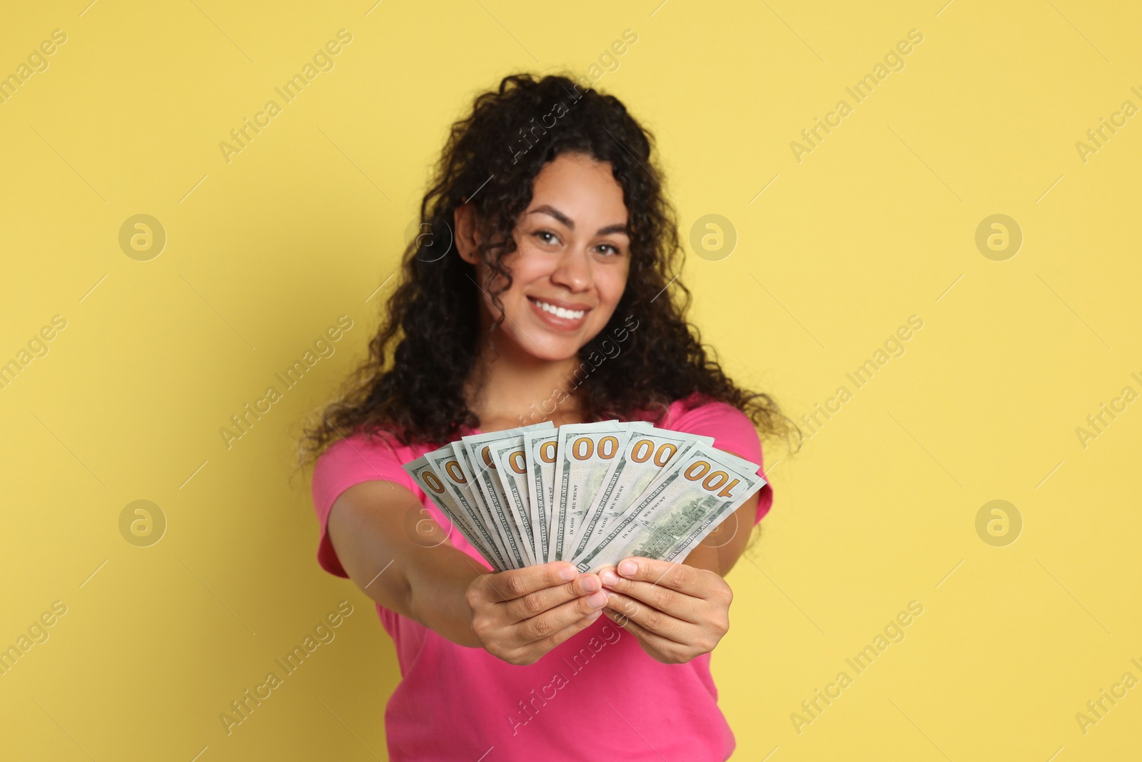 Photo of Happy woman with dollar banknotes on yellow background