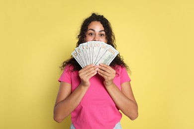 Woman with dollar banknotes on yellow background