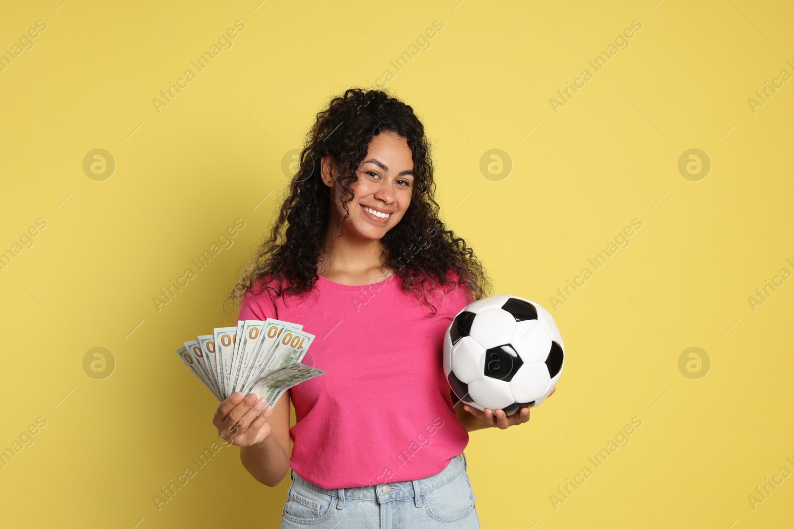 Photo of Happy woman with money and soccer ball on yellow background