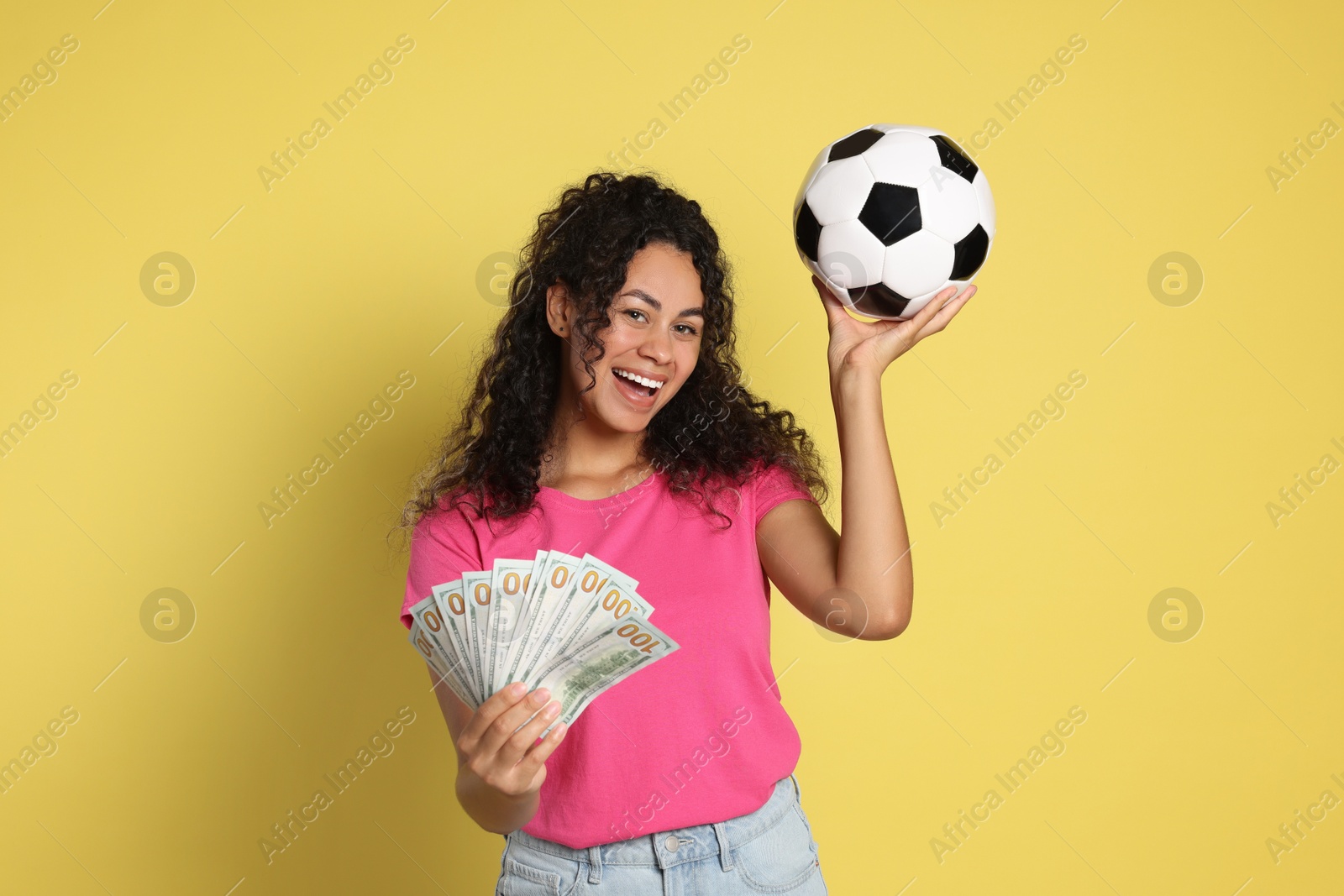 Photo of Happy woman with money and soccer ball on yellow background