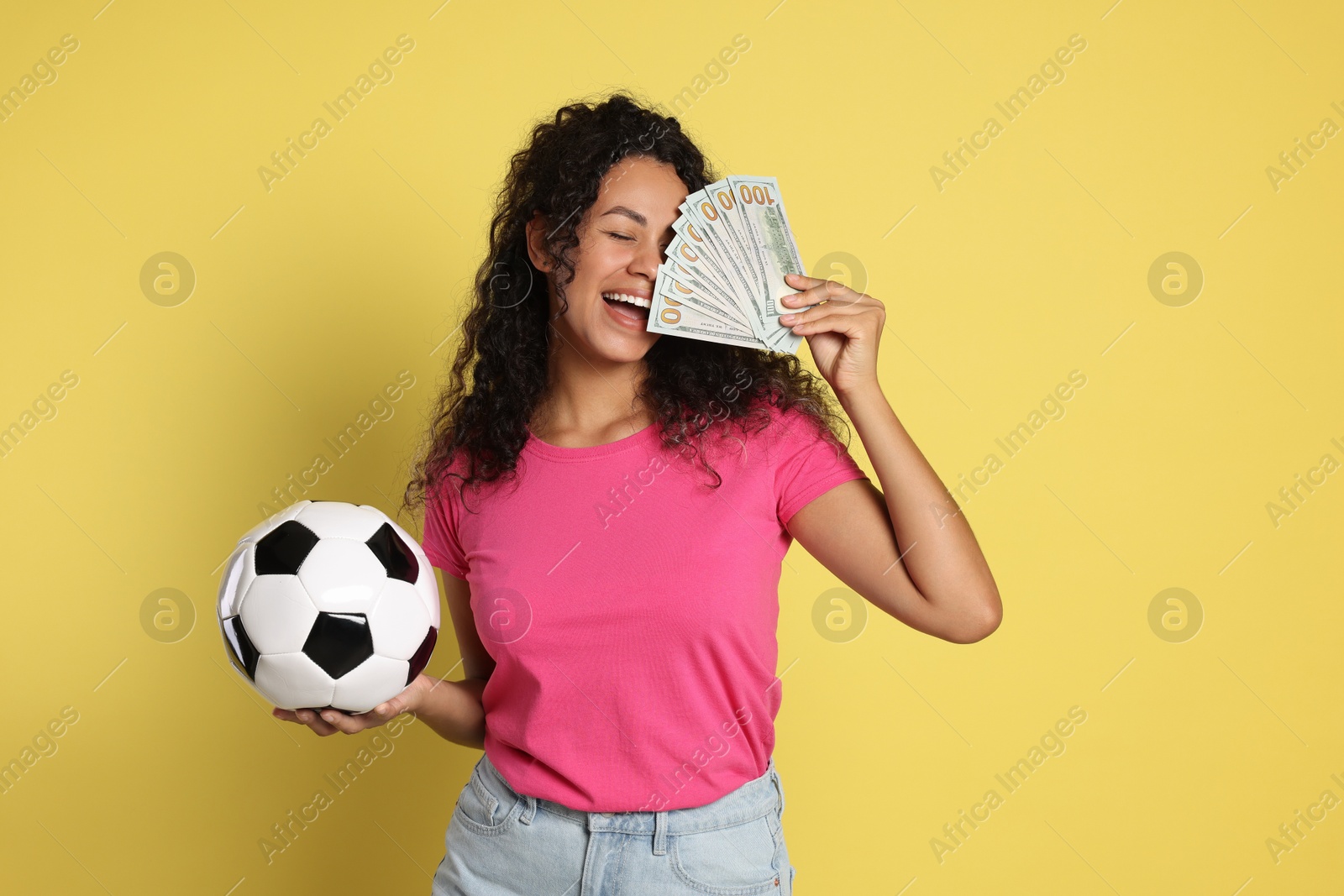 Photo of Happy woman with money and soccer ball on yellow background