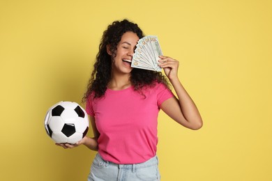 Photo of Happy woman with money and soccer ball on yellow background