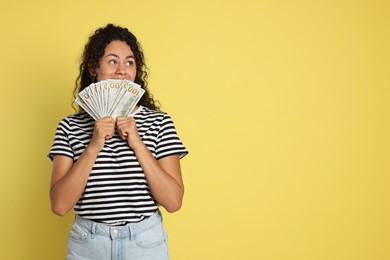 Woman with dollar banknotes on yellow background, space for text