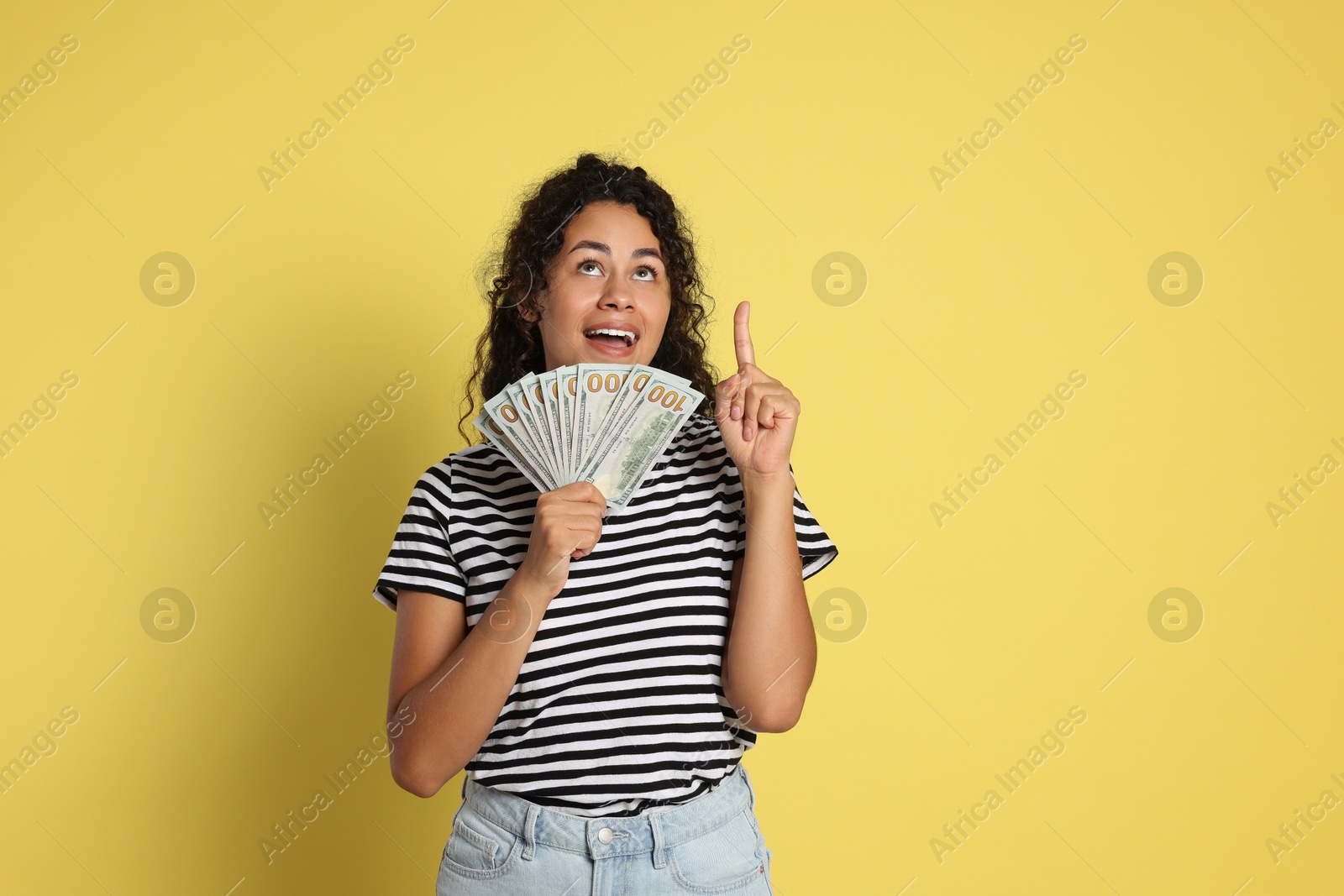 Photo of Happy woman with dollar banknotes on yellow background