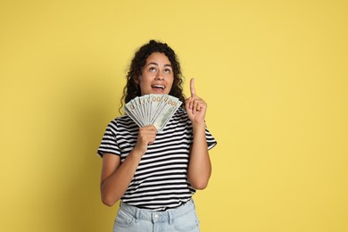 Happy woman with dollar banknotes on yellow background