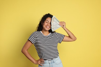 Photo of Happy woman with dollar banknotes on yellow background