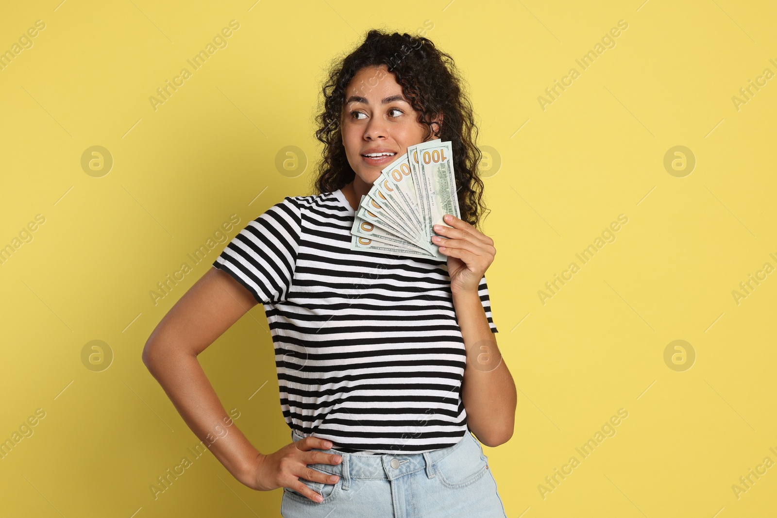 Photo of Happy woman with dollar banknotes on yellow background