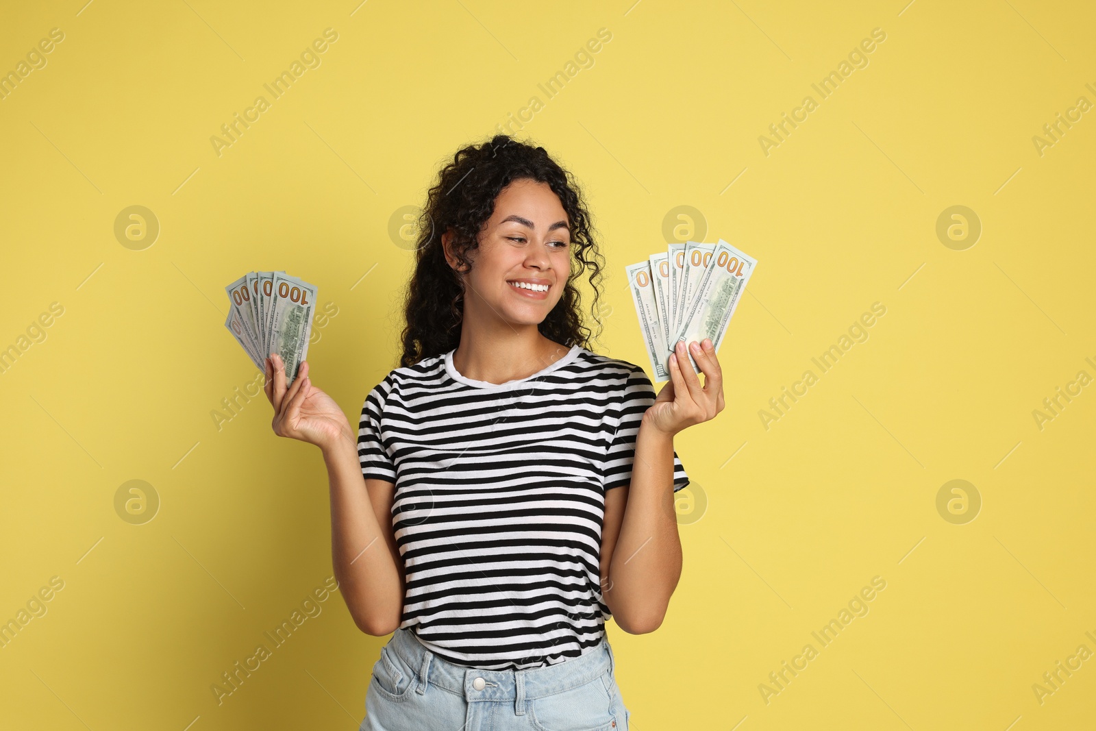 Photo of Happy woman with dollar banknotes on yellow background