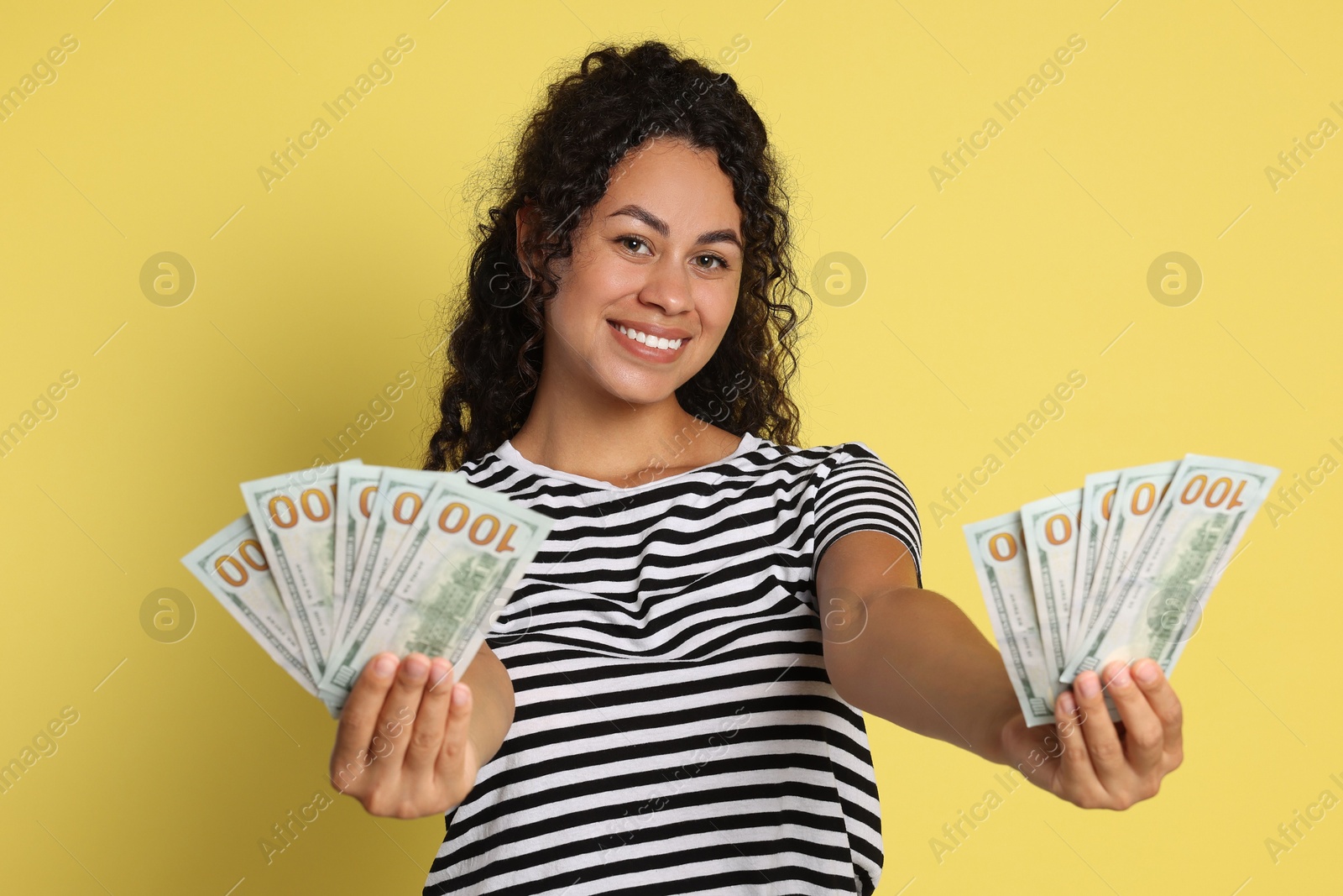 Photo of Happy woman with dollar banknotes on yellow background