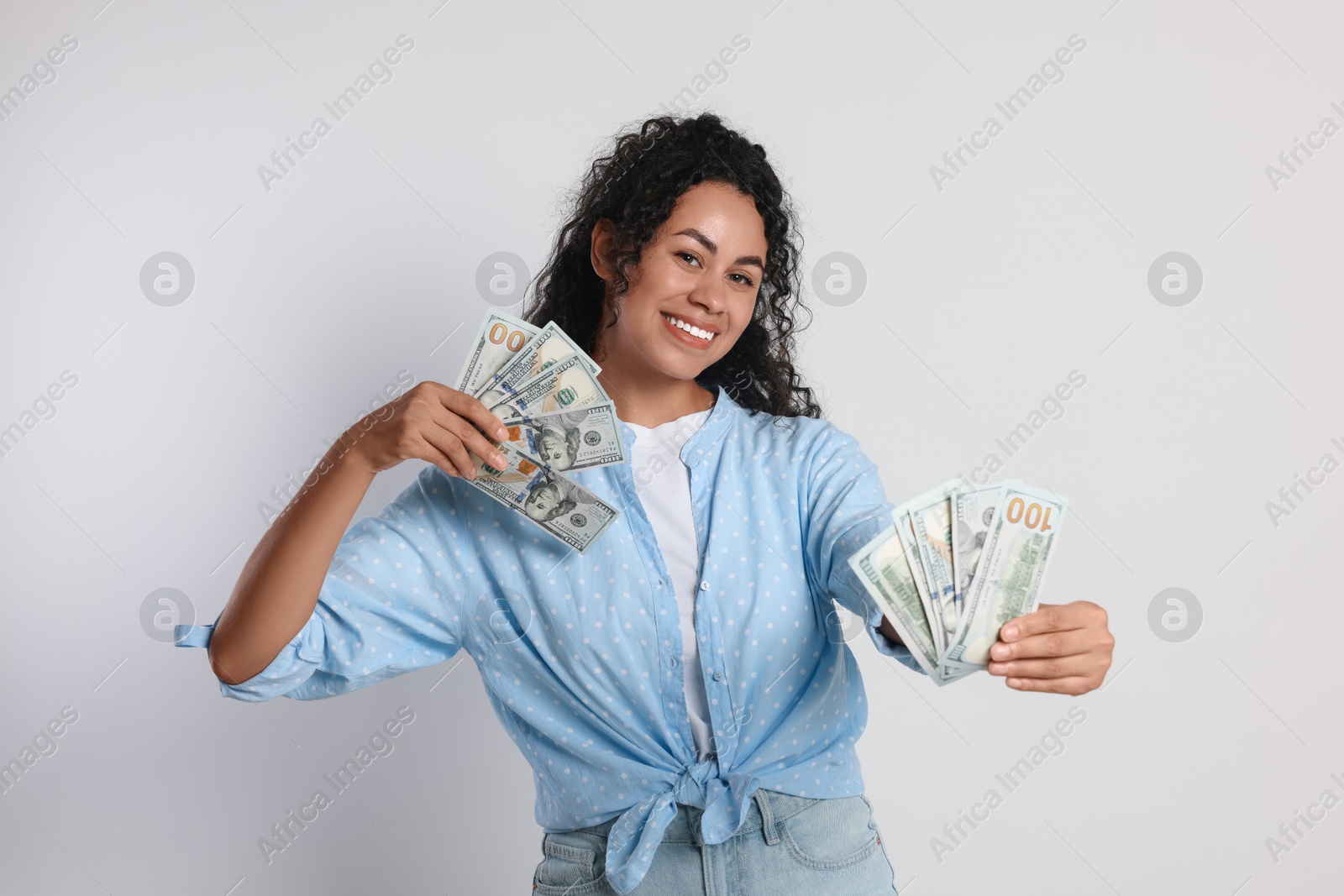 Photo of Happy woman with dollar banknotes on light grey background