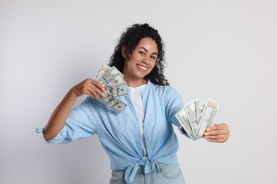 Photo of Happy woman with dollar banknotes on light grey background