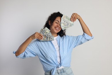 Photo of Happy woman with dollar banknotes on light grey background