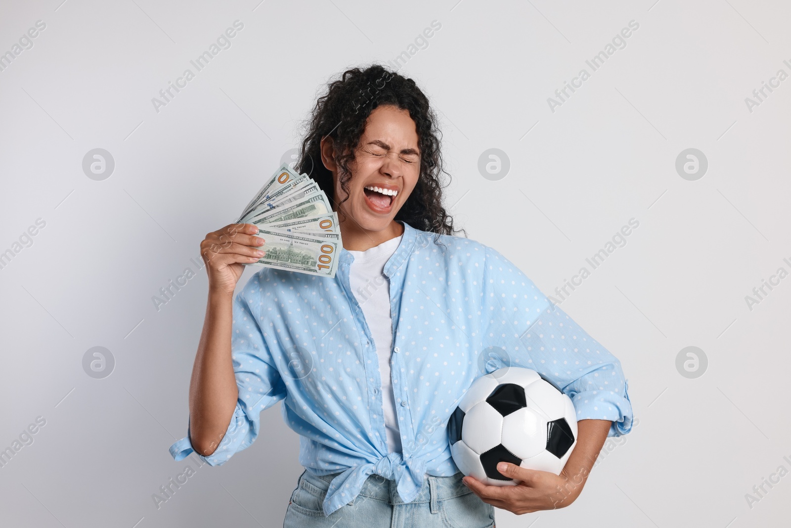 Photo of Happy woman with money and soccer ball on light grey background