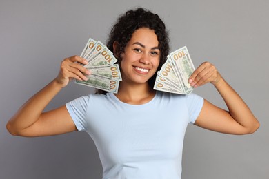 Happy woman with dollar banknotes on grey background