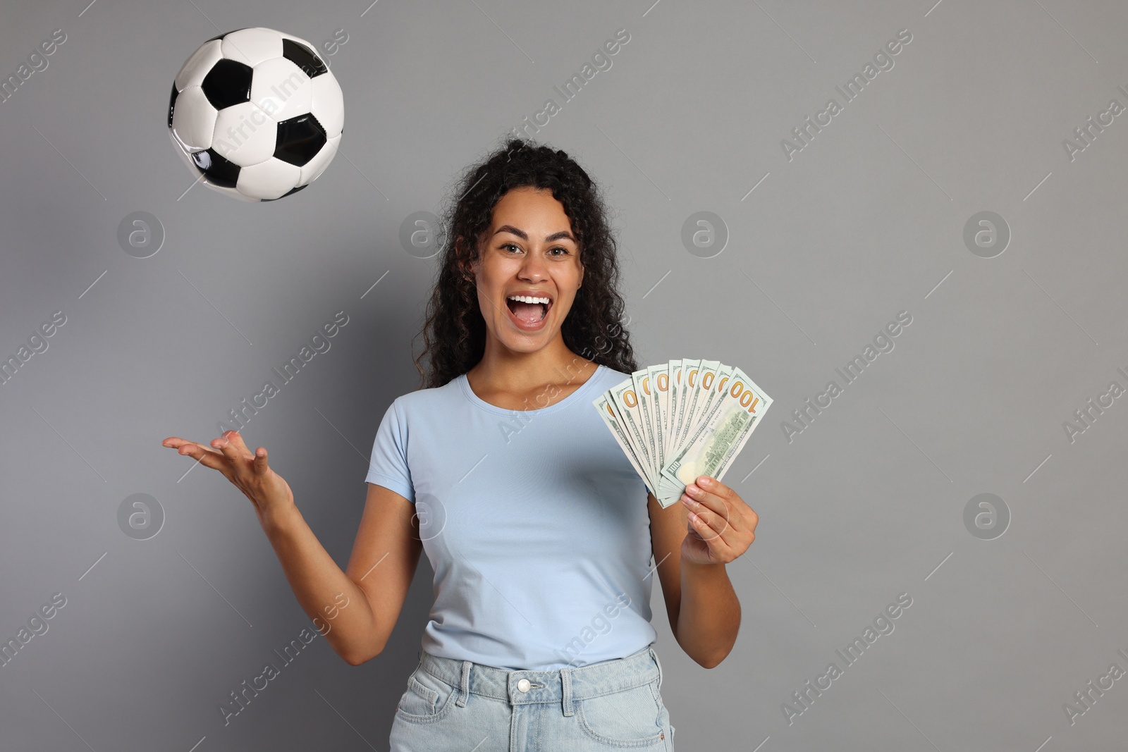 Photo of Happy woman with money throwing soccer ball on grey background