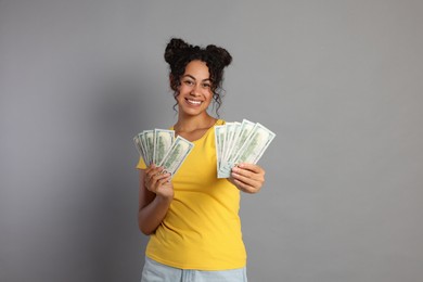 Happy woman with dollar banknotes on grey background