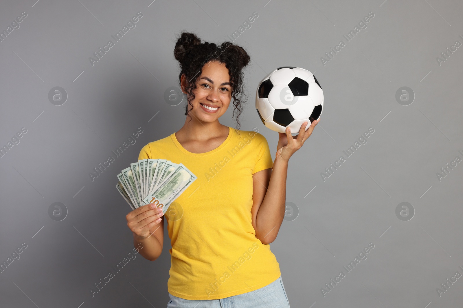 Photo of Happy woman with money and soccer ball on grey background