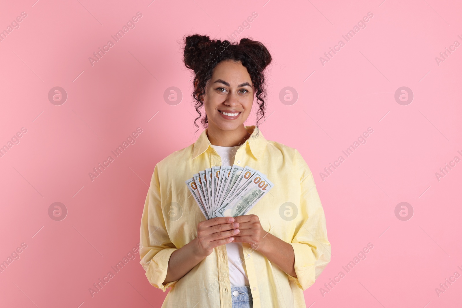 Photo of Happy woman with dollar banknotes on pink background