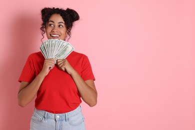 Photo of Happy woman with dollar banknotes on pink background, space for text