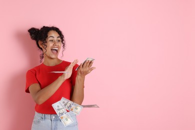 Happy woman throwing money on pink background, space for text