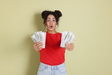 Photo of Shocked woman with dollar banknotes on pale green background