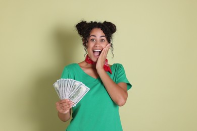 Photo of Happy woman with dollar banknotes on pale green background