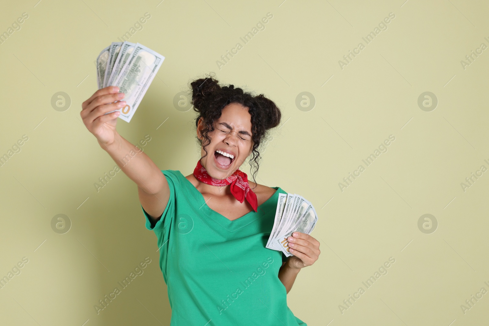 Photo of Happy woman with dollar banknotes on pale green background