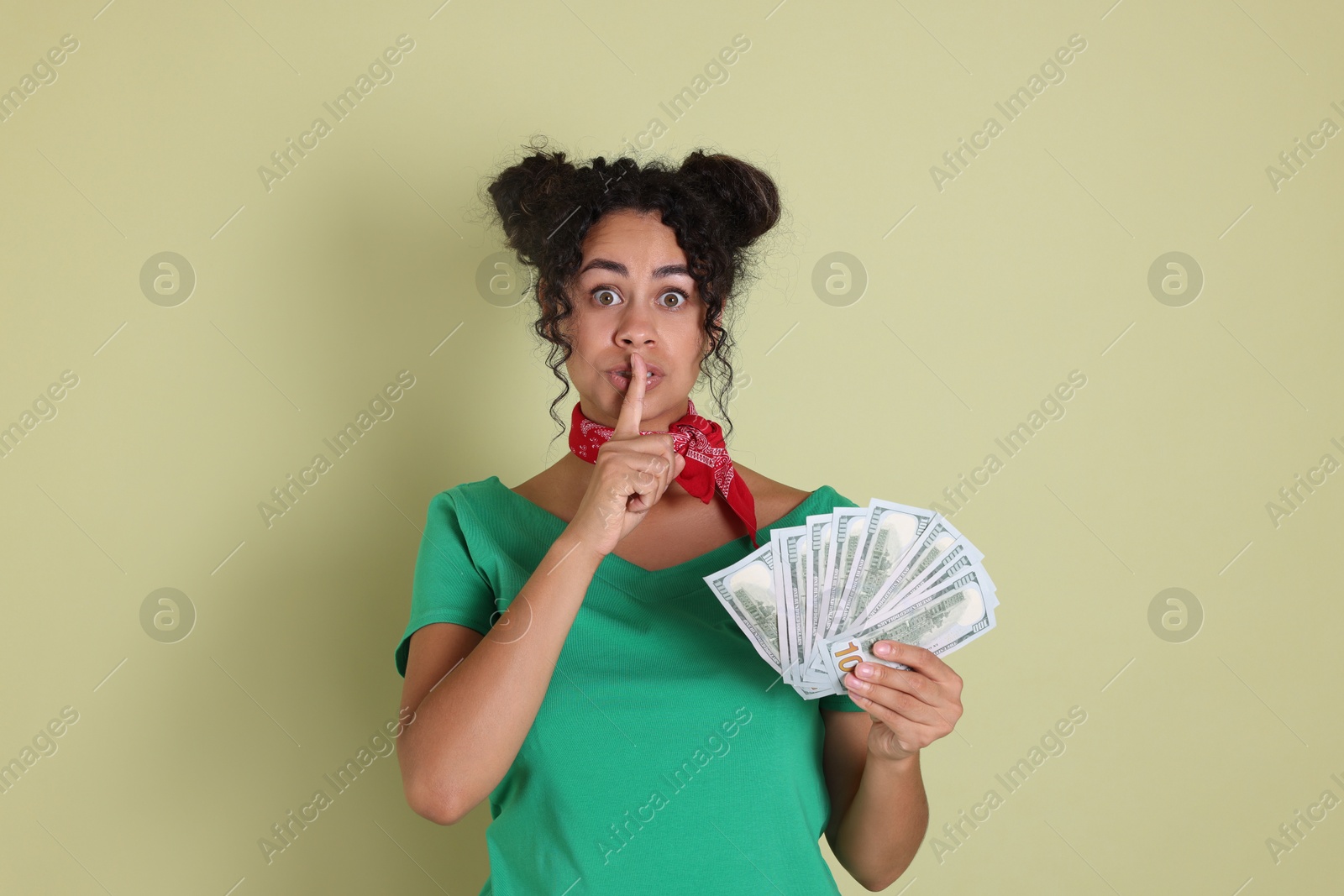 Photo of Woman with dollar banknotes making silent gesture on pale green background