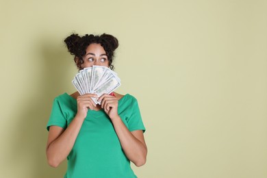 Woman with dollar banknotes on pale green background, space for text