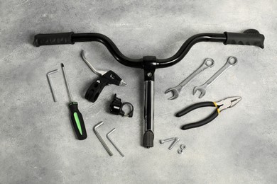 Parts of bicycle and tools on grey background, flat lay