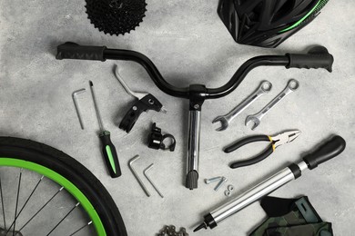 Parts of bicycle and tools on grey background, flat lay